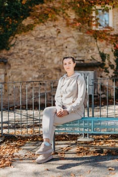 Attractive young woman sitting on a bench enjoying a view of medieval town in Europe. Summer holidays concept.