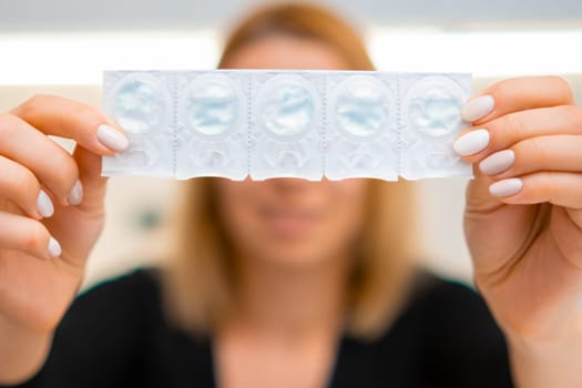 Smiling woman holding a blister with eye lenses in front of yourself. Disposable eye lenses in the solution.