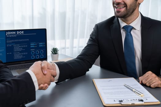 Two professionals successfully close business deal with closeup handshake, sealing the partnership agreement. Legal document and handshaking as formal agreement between two companies. Fervent