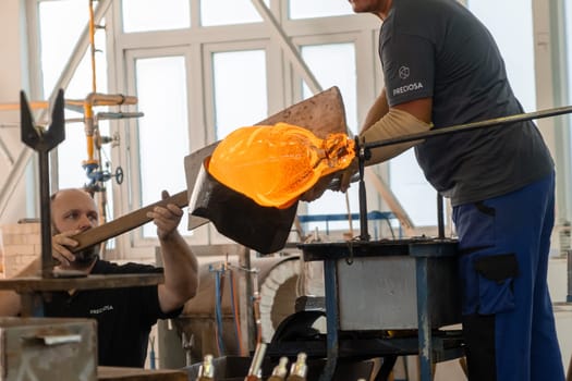 Manual glass production by glassblowing by worker at the factory.