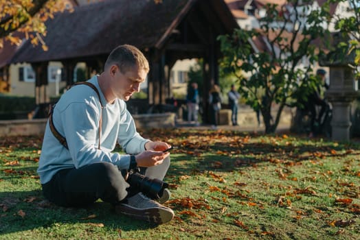 Professional photographer taking picture of beautiful autumn park. man professional photographer sit with camera in autumn park