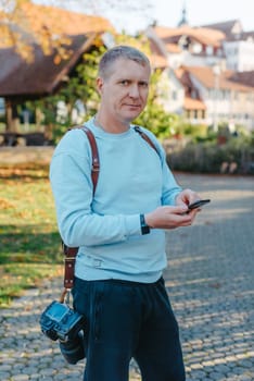 Professional photographer taking picture of beautiful autumn park. man professional photographer sit with camera in autumn park