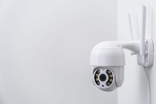 Round CCTV camera with antennas shoots video on the white wall. Digital equipment to record and broadcast real time video closeup