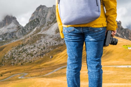 Legs of hiking woman standing and holding a retro camera on the peak of the mountain covered by clouds. Travel concept.