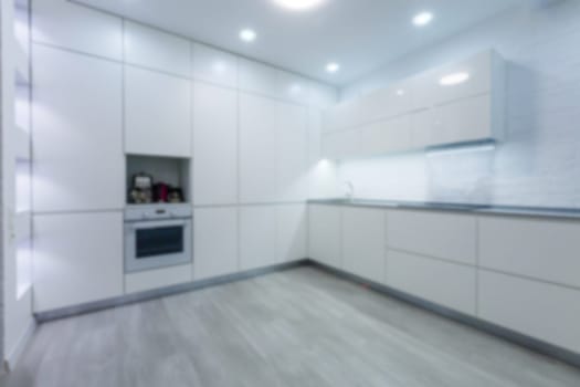 Blurred view of modern kitchen interior with white furniture. High quality photo