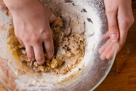 Close up of woman baker hands kneading the dough in the mixing bowl. Homemade pastry for cakes or cookies.