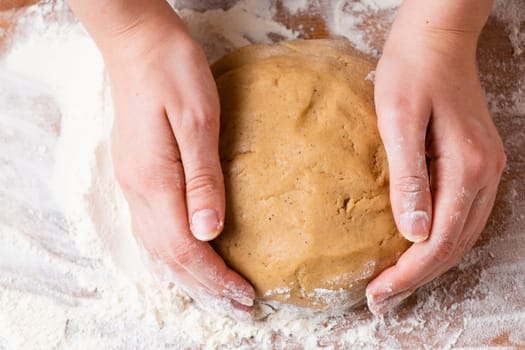 Top view of woman hands kneading the dough for buns, pie, cookies or pastry on the wooden desk. Process of homemade cooking.