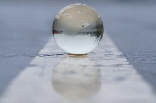 Glass globe on wet asphalt with markings. Globalization concept.