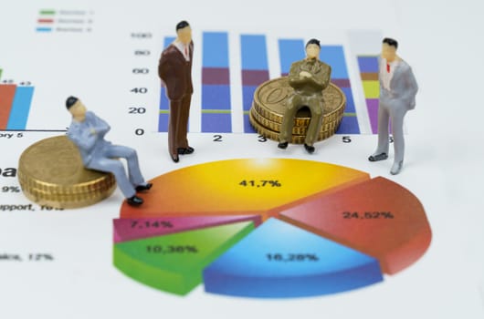Business concept. On financial charts there are miniature figures of businessmen, they sit on coins. Review the chart.
