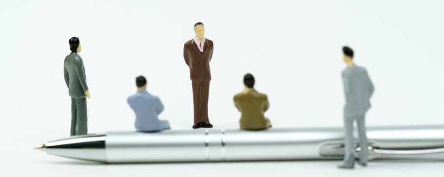Business and finance concept. On a white surface are miniature figures of businessmen - holding a meeting, a seminar. Some businessmen are sitting on the handle, others are standing.