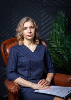 Portrait of a successful female psychologist in her office, notebook in hand, in her chair