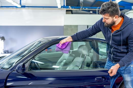 manual cleaning of car windows with a microfiber towel in the garage. High quality photo