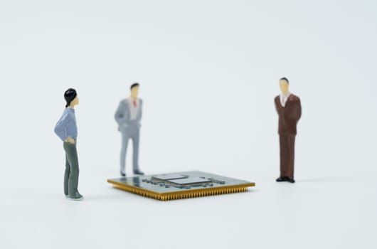 Technological concept. On a white surface lies a processor around which are miniature figures of people.