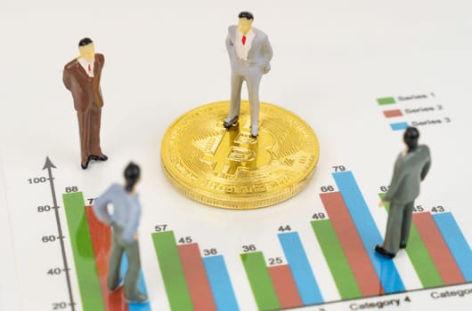 Cryptocurrency and business concept. On the business charts are bitcoins and miniature figures of people.