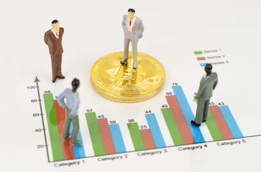 Cryptocurrency and business concept. On the business charts are bitcoins and miniature figures of people.