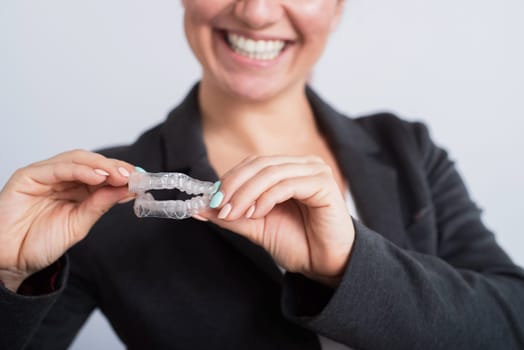 Smiling business woman holding two transparent aligners.