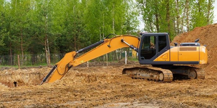 Building concept. An excavator is digging a pit for a house.