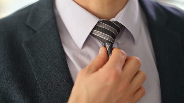 Businessman manager in suit straightening tie on shirt in office closeup. Business elegant style concept