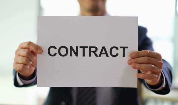 Businessman holding paper document contract in hands in office closeup. Employment and profitable deals concept