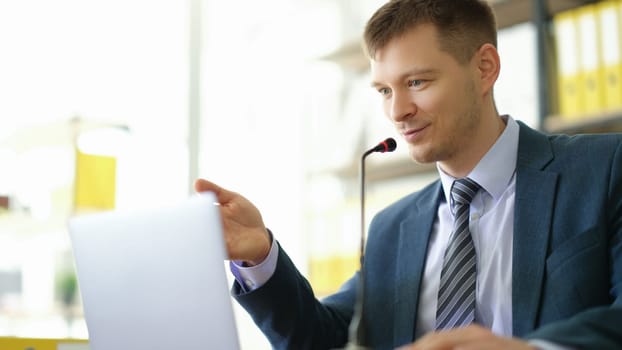 Business coach speaking into microphone in front of laptop via video call. Video conference online concept