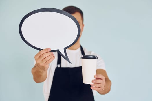 Holding drink in hand. Man standing in the studio with empty signs for the text.