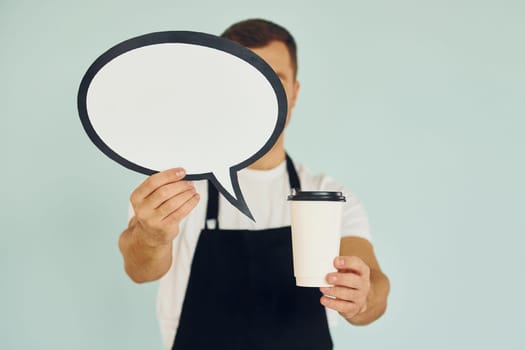 Holding drink in hand. Man standing in the studio with empty signs for the text.