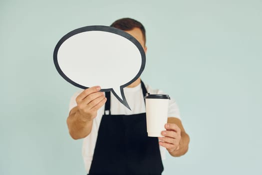 Holding drink in hand. Man standing in the studio with empty signs for the text.