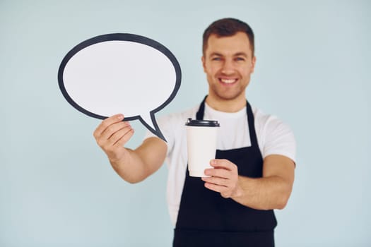 Holding drink in hand. Man standing in the studio with empty signs for the text.