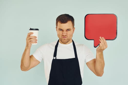 Angry and holding drink in hand. Man standing in the studio with empty signs for the text.