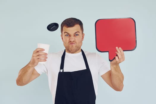 Angry and holding drink in hand. Man standing in the studio with empty signs for the text.
