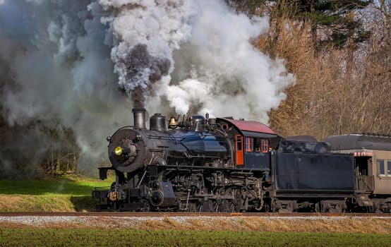 A View of a Classic Steam Passenger Train, Blowing Lots of Smoke and Steam, While Traveling in the Countryside on an Autumn Day