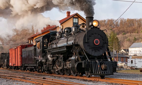 View of a Restored, Antique Steam Freight Train Approaching in Early Morning, on old Narrow Gauge Tracks on a Winter Day, Blowing Smoke