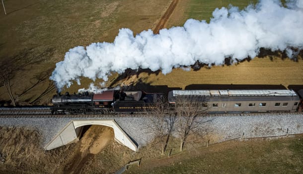 Ronks, Pennsylvania, December 28, 2022 - Aerial Parallel View of a Restored Antique Steam Passenger Train Traveling Thru The Countryside on a Sunny Autumn Day