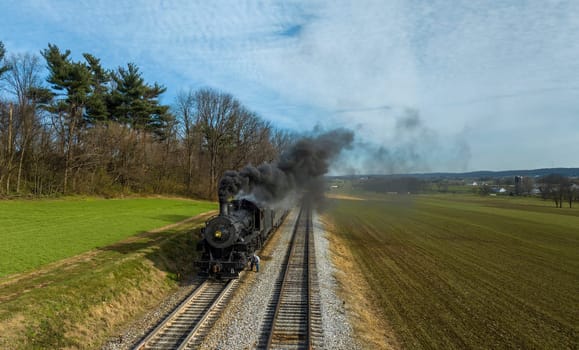 A Head on Aerial View of a Steam Engine Waiting, all Steamed Up, While the Engineer Checks and Oils the Engine, While it is Blowing Smoke on a Winter Day