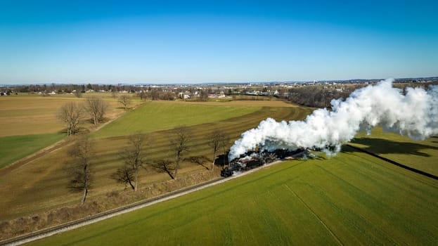 An Aerial View of a Steam Double-Header Freight , Passenger Combo Train Approaching Blowing Lots of Smoke and Steam on a Sunny Winter's Day