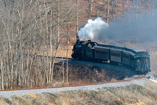 View of a Narrow Gauge Restored Steam Passenger Train Blowing Smoke and Traveling Thru Farmlands on a Winter Day