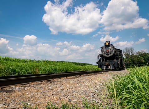 A Low Angle View of a Steam Locomotive Approaching on a Single Track on a Sunny Summer Day
