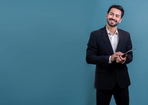 Confident businessman in formal suit holding tablet with surprise look for promotion or advertising. Facial expression and gestures indicate excitement and amazement on an isolated background. Fervent