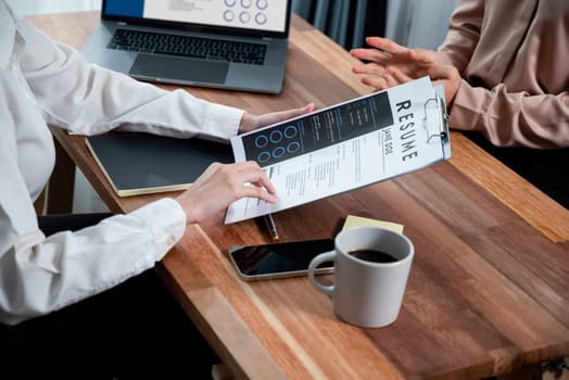 Closeup resume paper with qualifications on the desk during job interview in the office with young applicant candidates and interviewer, discussing on application of the position. Enthusiastic