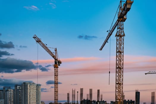 Large construction site with cranes working on a building complex, with sunset sky. download image