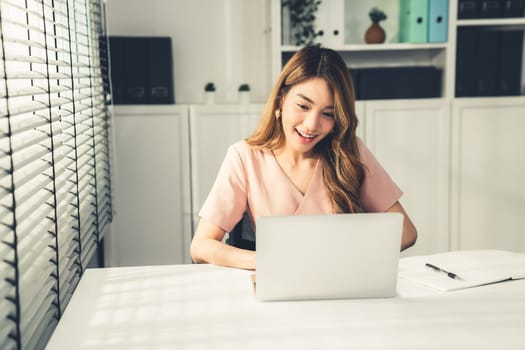 A young Asian female employee sitting at her desk in her office, sitting at desktop in workstation.