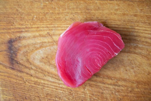 Raw tuna steak on a wooden board, top view. Delicious and healthy food for the body