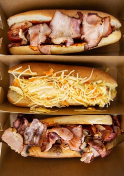 American hot dog with different flavors, with cheese and crispy onions on a white table in a minimalist style. Fast food, takeaway food, food for motorists. Hot dog sandwich with sausage, vertical photo