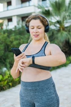 Fat woman checking time or heart rate from smart watch. Exercise or running outdoors for weight loss idea concept. Wellness and wellbeing concept