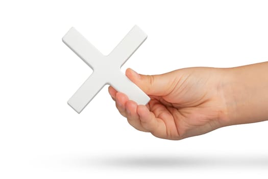 White multiplication symbol or cross in hand. The concept of prohibition or removal of something. Mathematical white multiplication symbol in hand on a white isolated background.