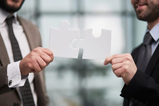 Working together to put things together. two unrecognizable businesspeople fitting puzzle pieces together in studio