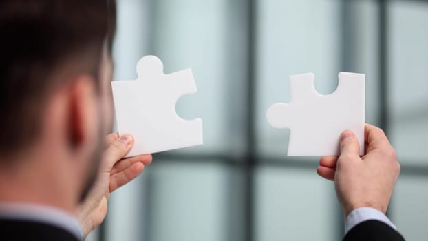 business hands of a businessman are assembling puzzle pieces.