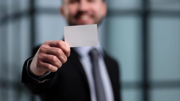 business man holding empty white business card in modern office building. Free blank copy space.