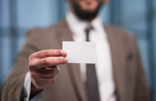 businessman with blank business card on office background