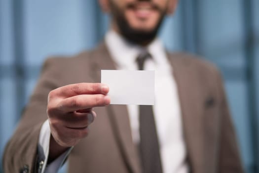 businessman with blank business card on office background